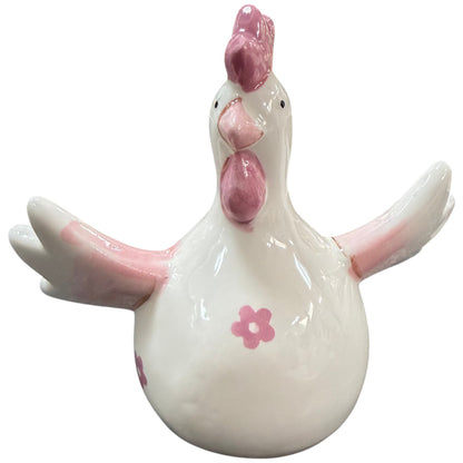 Dekoratives Keramik-Huhn in Cremeweiß mit rosa Details an Kamm, Flügeln und Schnabel. Die glänzende Oberfläche und kleine Blütenmotive verleihen der Figur einen verspielten, frühlingshaften Look.