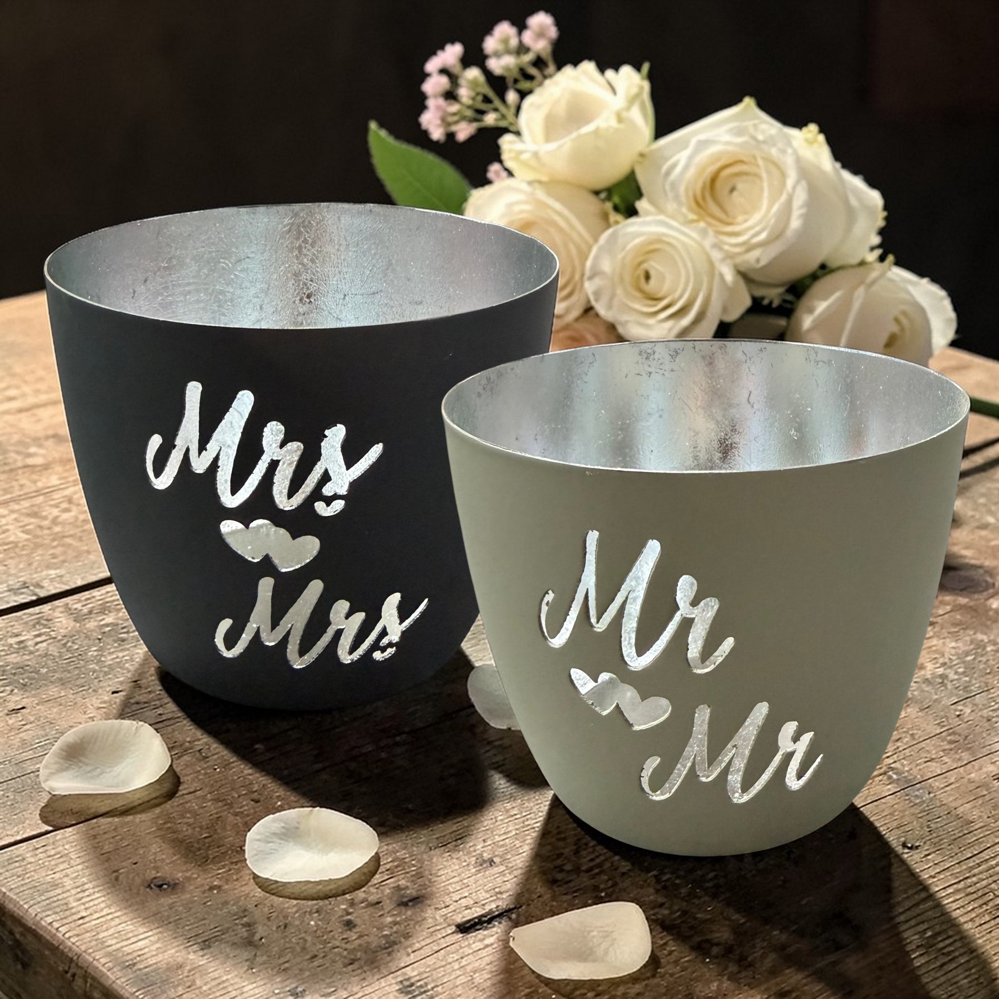 Zwei dekorative Metall-Windlichter mit silberner Innenseite und Schriftzügen „Mr & Mr“ sowie „Mrs & Mrs“.