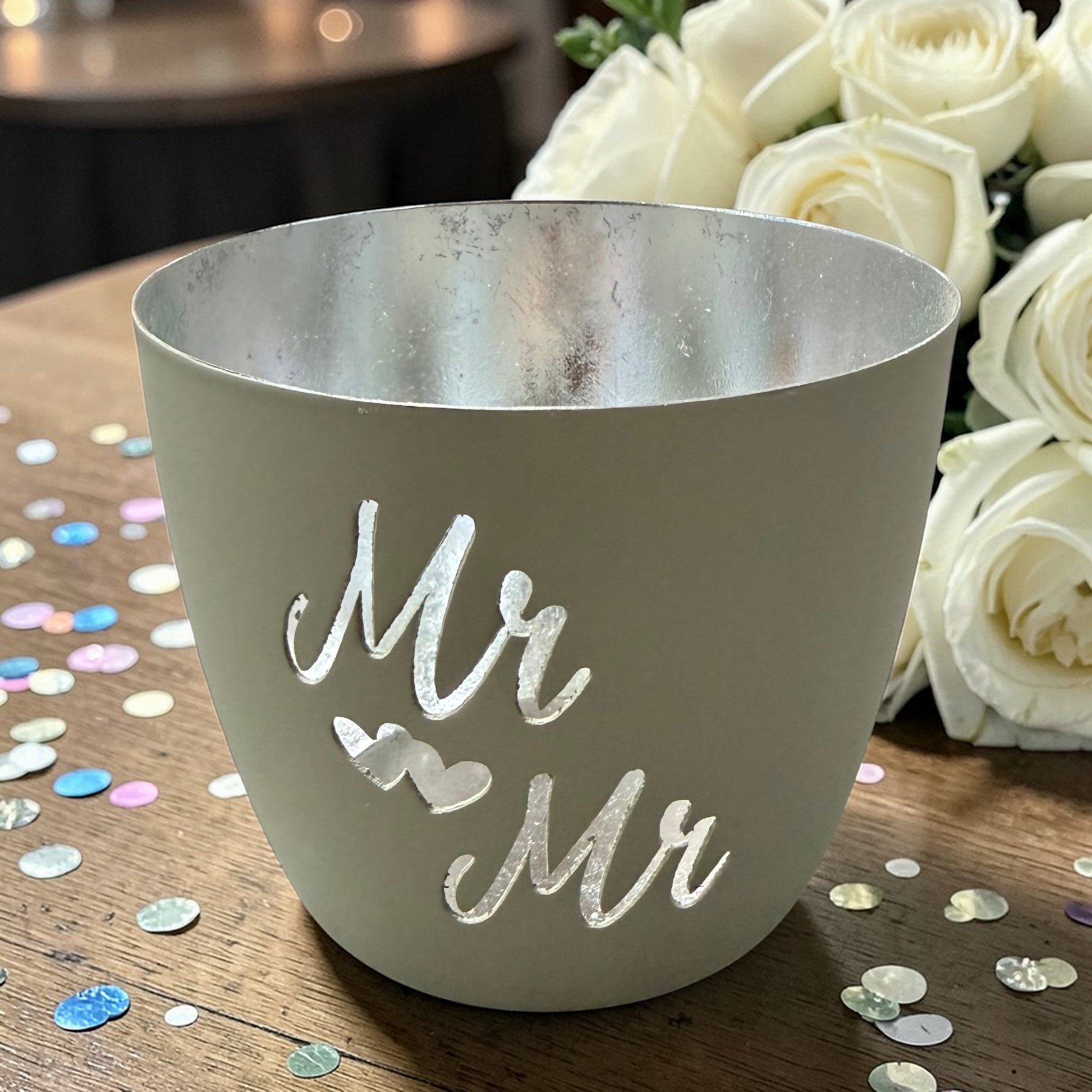Ein Windlicht aus Metall in Beige mit silberner Innenseite, freigestellt vor weißem Hintergrund, mit dem Schriftzug „Mr & Mr“.