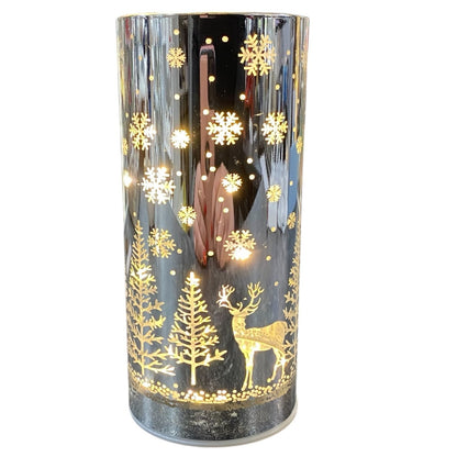 Zylindrisches silbernes LED-Licht mit goldenem Wintermotiv aus Tannen, Schneeflocken und einem Hirsch.