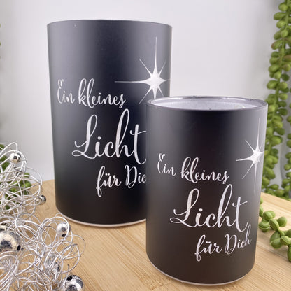 Zwei schwarze LED Dekolicht Säulen mit Spruch "Ein kleines Licht für Dich!" und kleinem Stern sind unterschiedlich groß und im Ambiente platziert. 