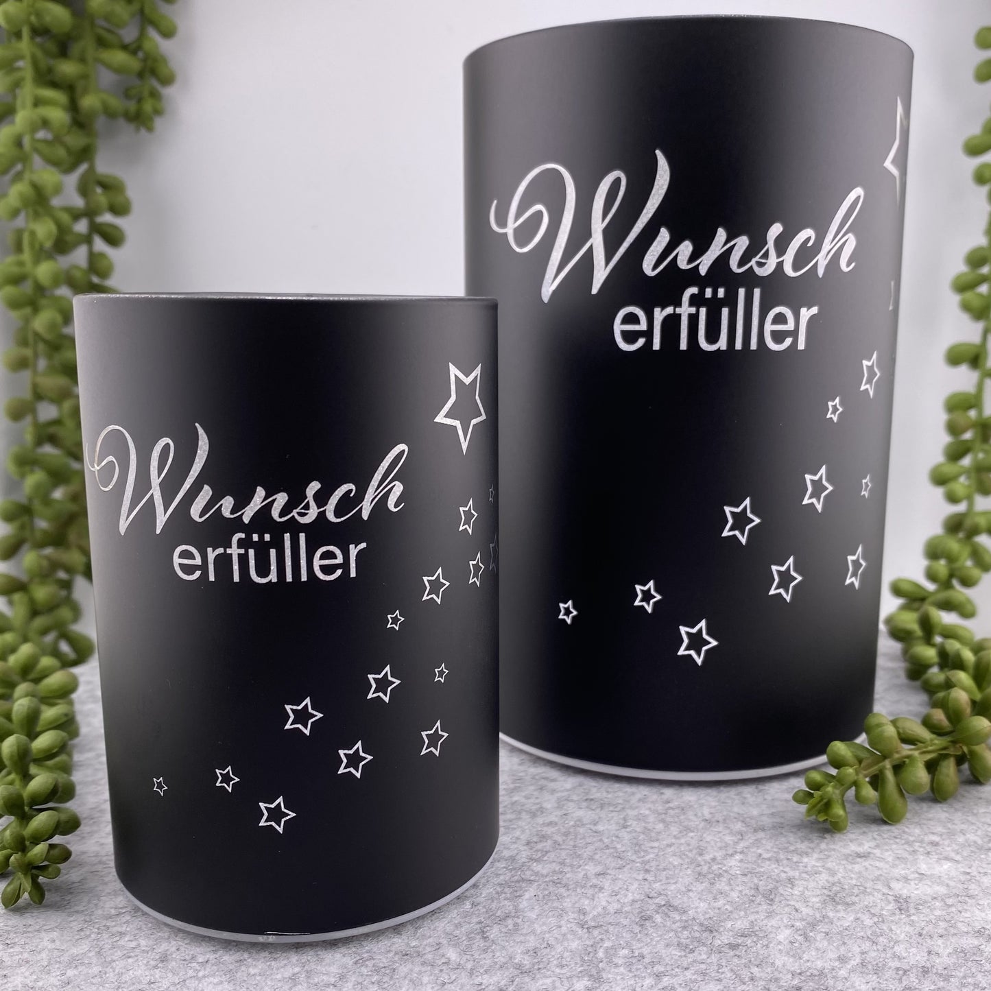 Zwei schwarze LED Dekolicht Säulen mit Spruch "Wunscherfüller" und kleinem Stern sind unterschiedlich groß und im Ambiente platziert.