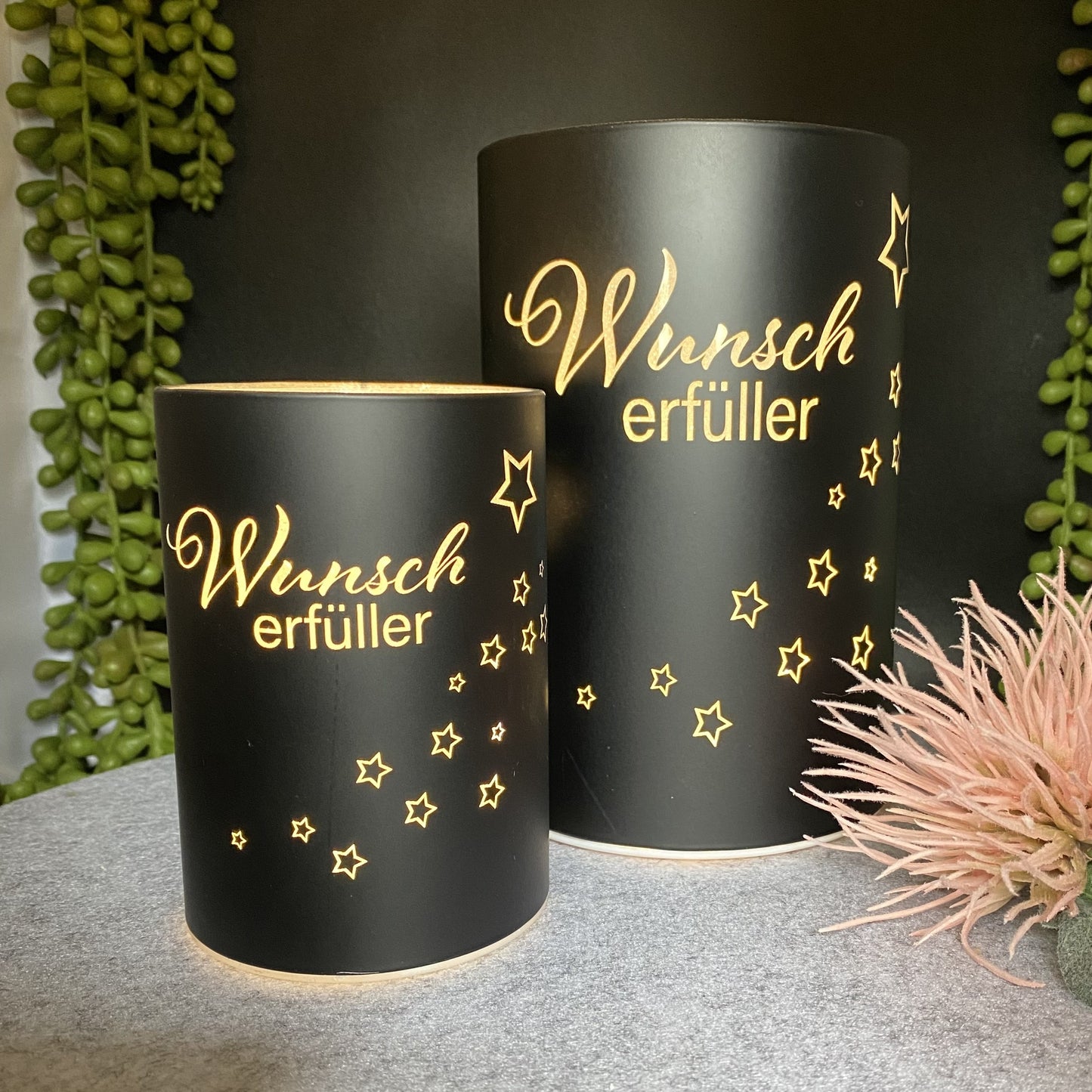 Zwei schwarze LED Dekolicht Säulen mit Spruch "Wunscherfüller" und kleinem Stern sind unterschiedlich groß und beleuchtet im Ambiente platziert.