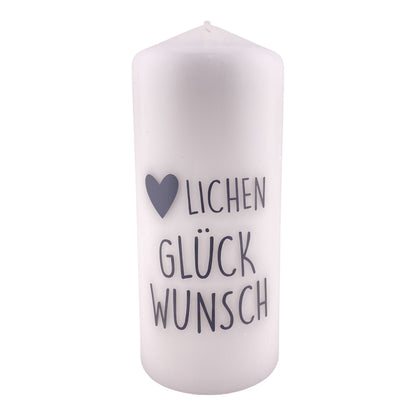 Eine große, weiße Kerze mit schwarzem Schriftzug "Herzlichen Glückwunsch". Die Dekokerze ist 18,5cm groß und vor weißem Hintergrund platziert.