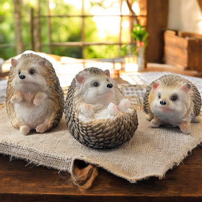 Realistische Igel-Figuren in drei Varianten, herbstlich dekoriert auf Leinentuch in gemütlicher Umgebung.