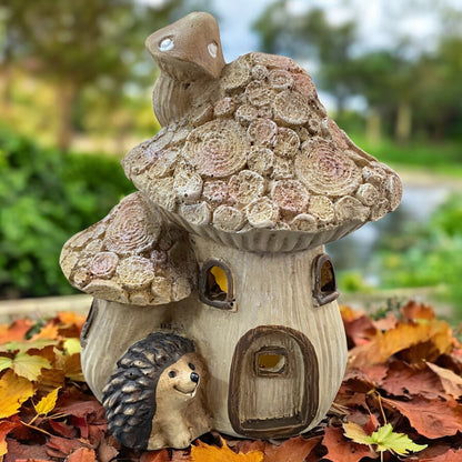 Großes Pilzhaus mit LED-Beleuchtung und Igelfigur, dekorativ im herbstlichen Garten mit buntem Laub arrangiert.