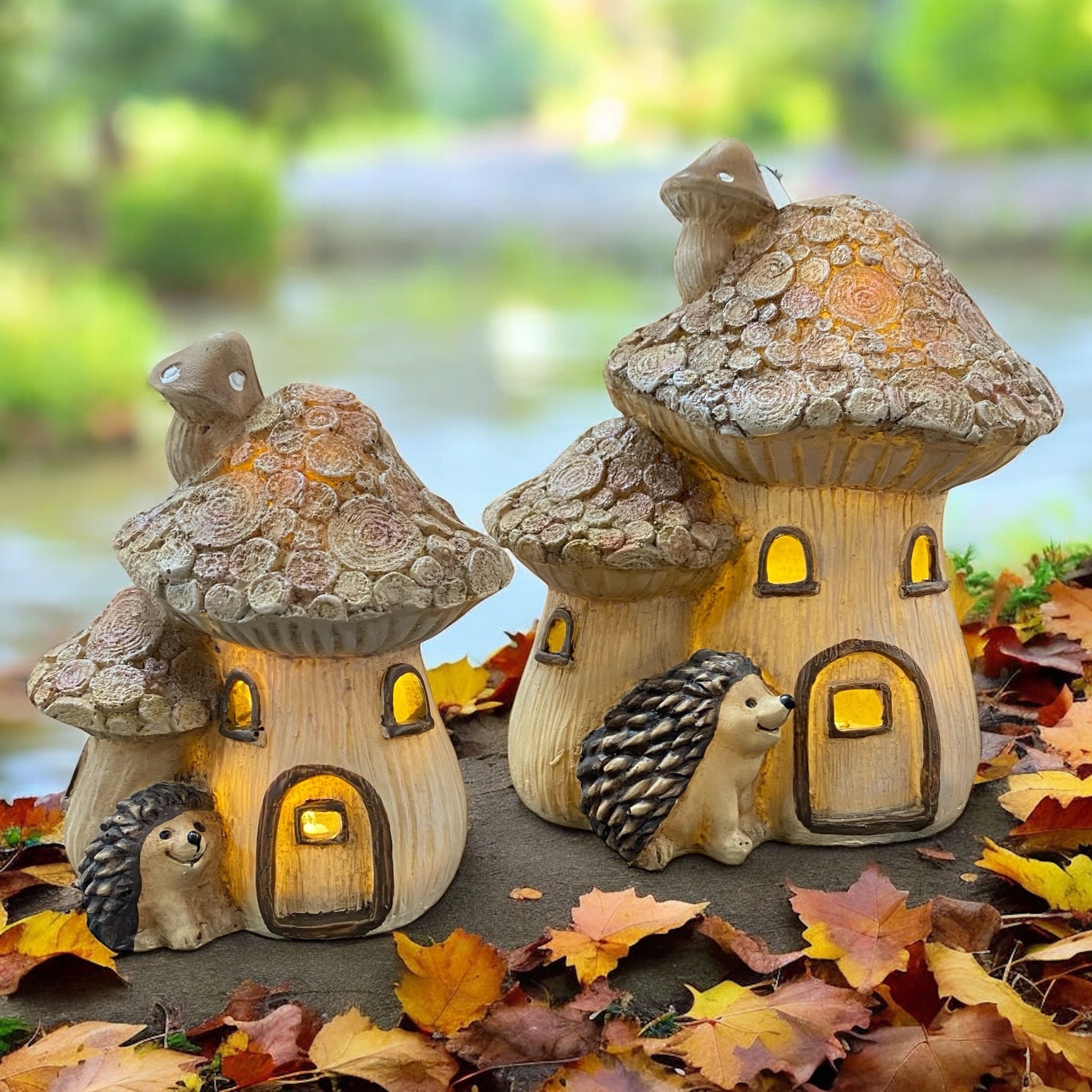 Beleuchtete Pilzhäuser mit Igeln als herbstliche Deko, stimmungsvoll zwischen buntem Herbstlaub platziert.