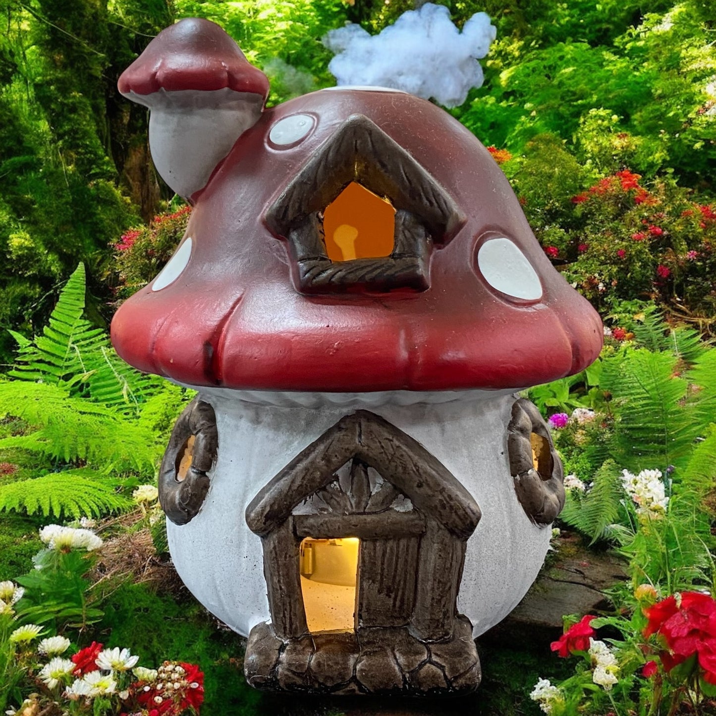 Rotes Pilzhaus mit LED-Beleuchtung, märchenhafte Herbstdekoration im Garten zwischen Farnen und Blüten.