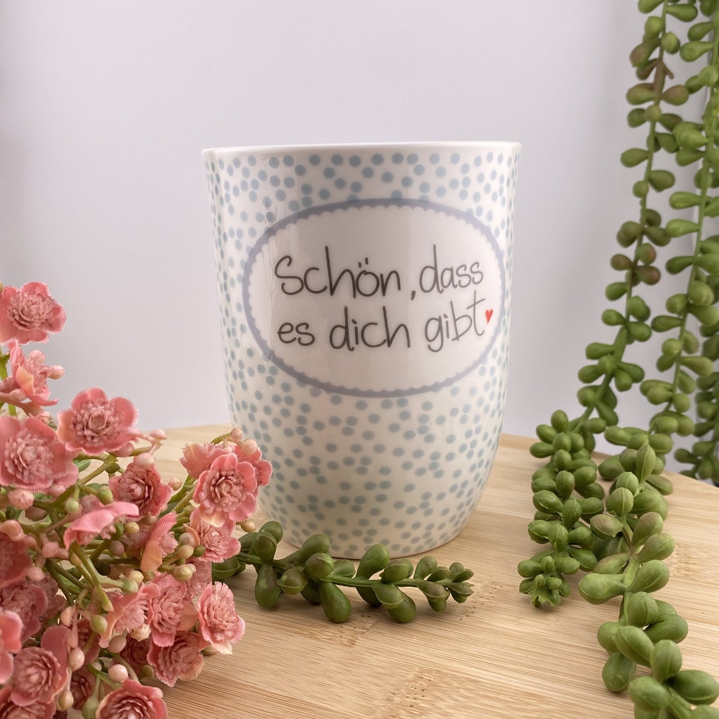 Eine blau weiß gepunktete Kaffeetasse mit Henkel und Schriftzug Schön, dass es dich gibt im Ambiente