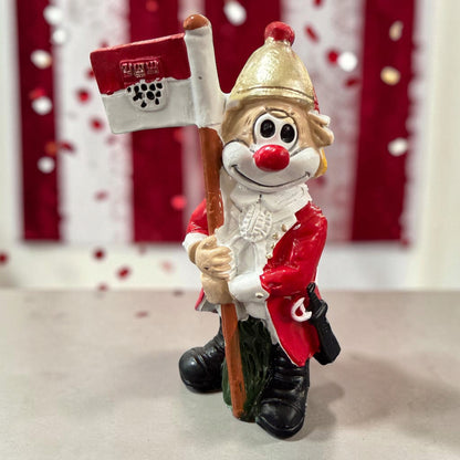 Karneval Deko Clown Die Schmitzens Fahnenträger mit rot-weißer Fahne vor rot-weißer Karnevalsdekoration.