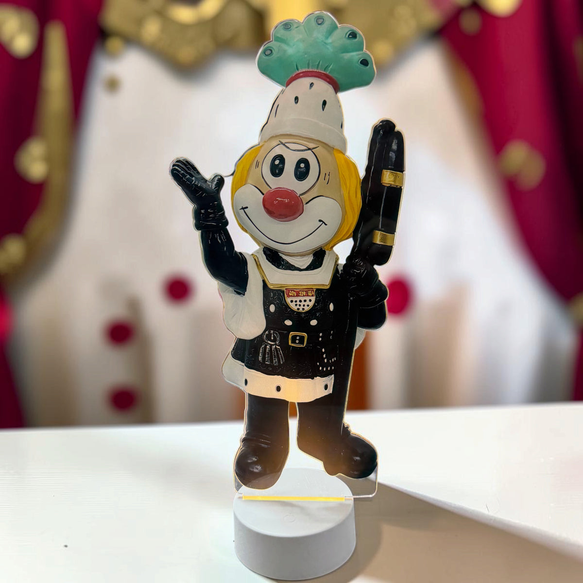 Schmitzens Karneval Deko Lampe Bauer mit schwarzer Kleidung, grüner Federkrone und beleuchtetem weißem Sockel.