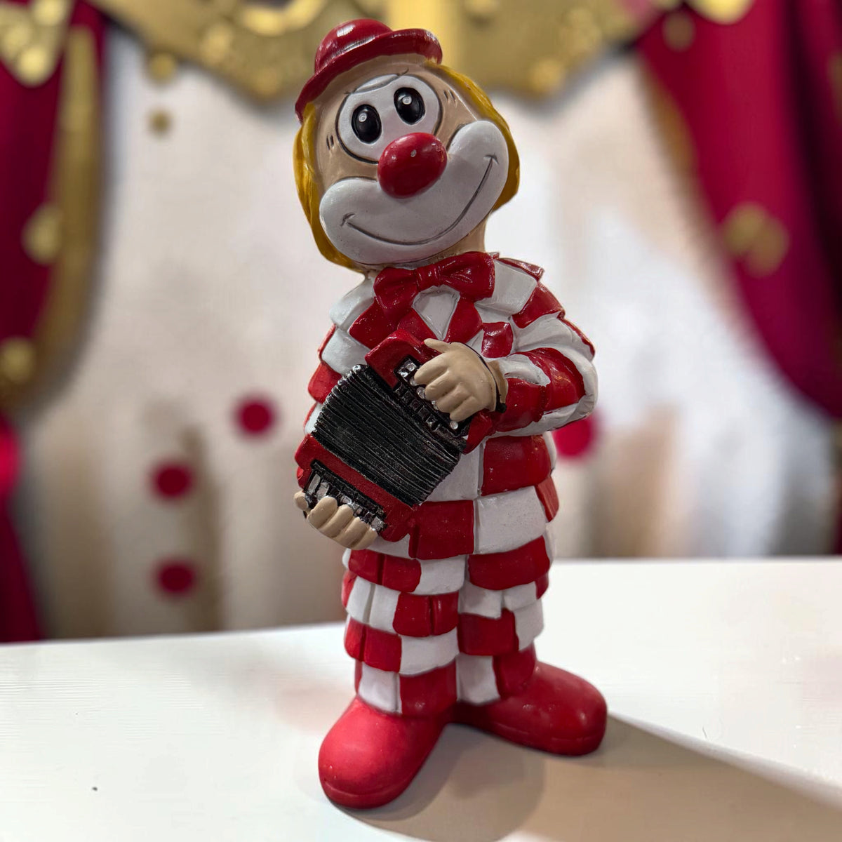 Karneval Deko Clown Die Schmitzens Lappenclown 20 cm mit schwarzem Akkordeon vor rot-weißer Karnevalsdekoration