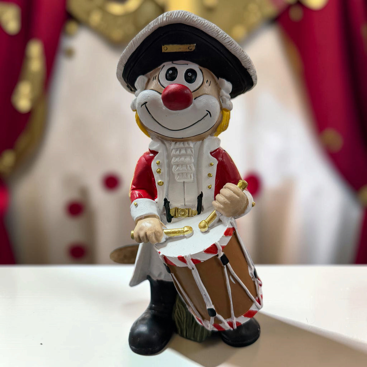 Großer Karneval Deko Clown Die Schmitzens Trommler mit Trommel vor rot-weißer Karnevalsdekoration.