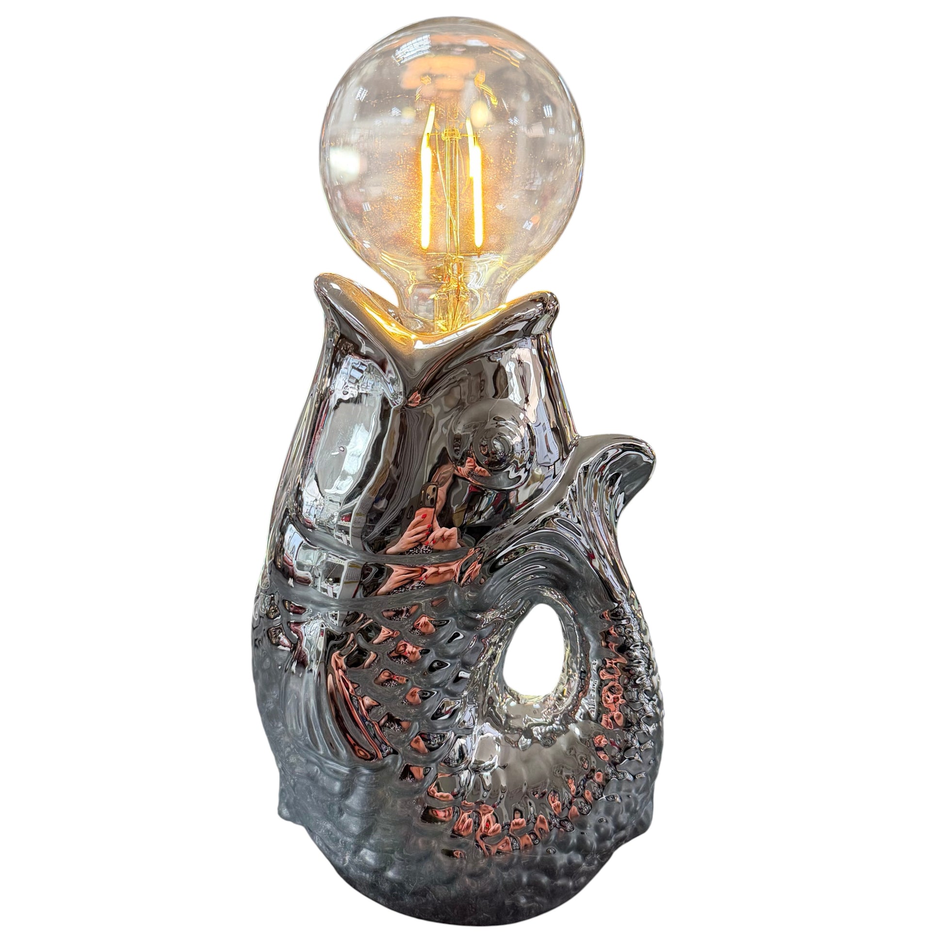 Moderne Tischlampe in Fischform aus glänzender silberfarbener Keramik mit sichtbarer LED-Glühbirne im Vintage-Stil, freigestellt vor weißem Hintergrund.