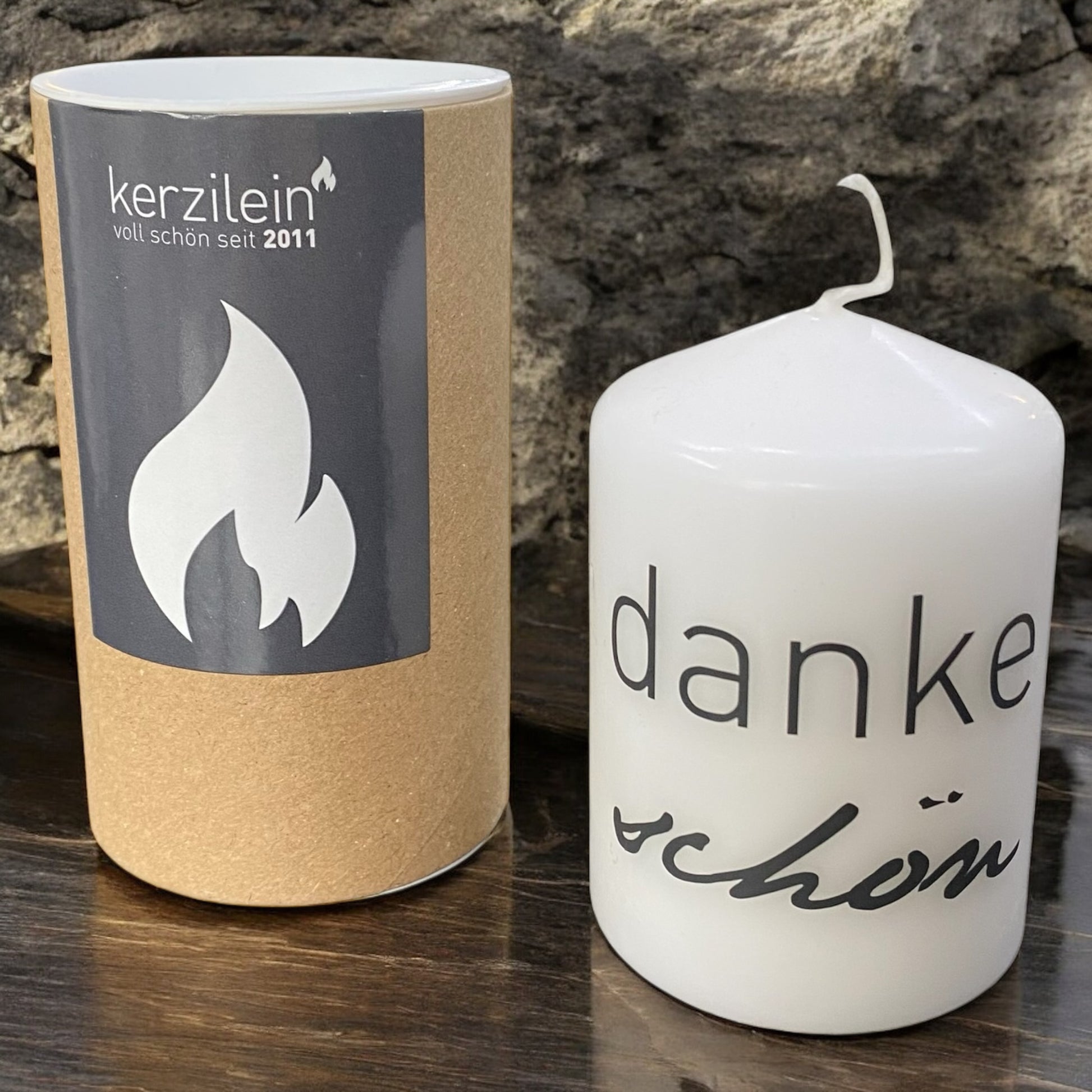 Weiße Stumpenkerze mit schwarzem Schriftzug „dankeschön“ im Ambiente