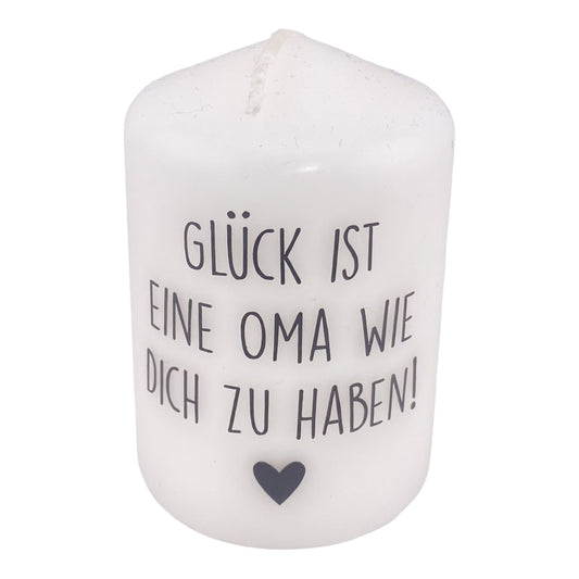 Eine kleine, weiße Kerze mit schwarzem Schriftzug "Glück ist eine Oma wie dich zu haben". Die Dekokerze ist 8cm groß und vor weißem Hintergrund platziert.