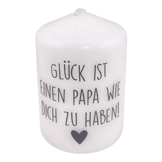 Eine kleine, weiße Kerze mit schwarzem Schriftzug "Glück ist ein Papa wie dich zu haben". Die Dekokerze ist 8cm groß und vor weißem Hintergrund platziert.