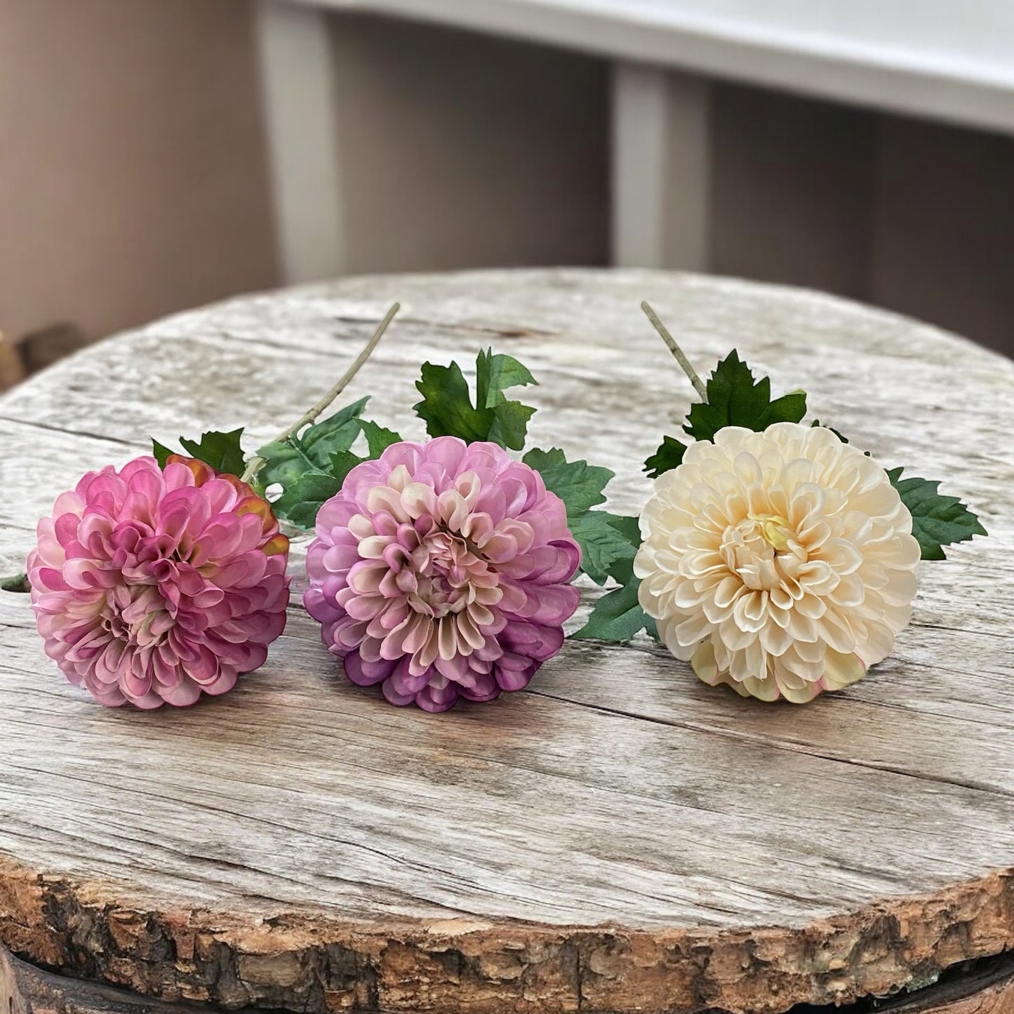 Drei künstliche Dahlienblüten in Rosa, Lila und Creme mit grünem Blattwerk und Stiel im Ambiente