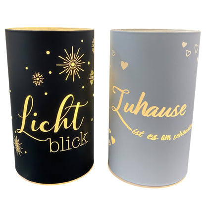 Zwei LED-Deko-Lichtsäulen in Schwarz und Weiß mit goldenen Sprüchen „Lichtblick“ und „Zuhause ist es am schönsten“.