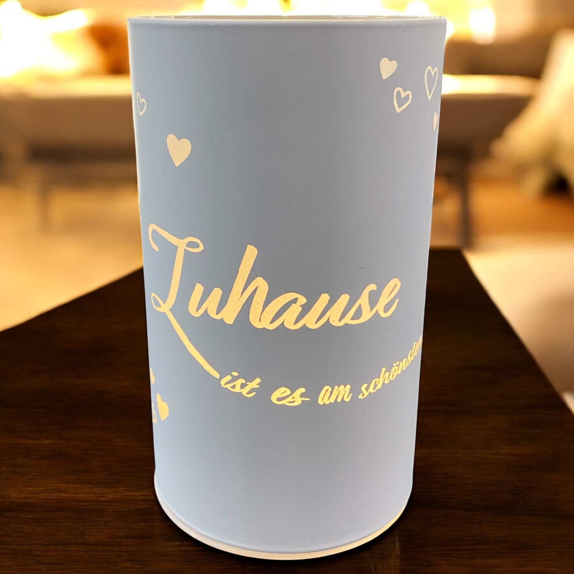 Weiße LED-Lichtsäule mit dem goldenen Spruch „Zuhause ist es am schönsten“ in gemütlicher Wohnraum-Atmosphäre.