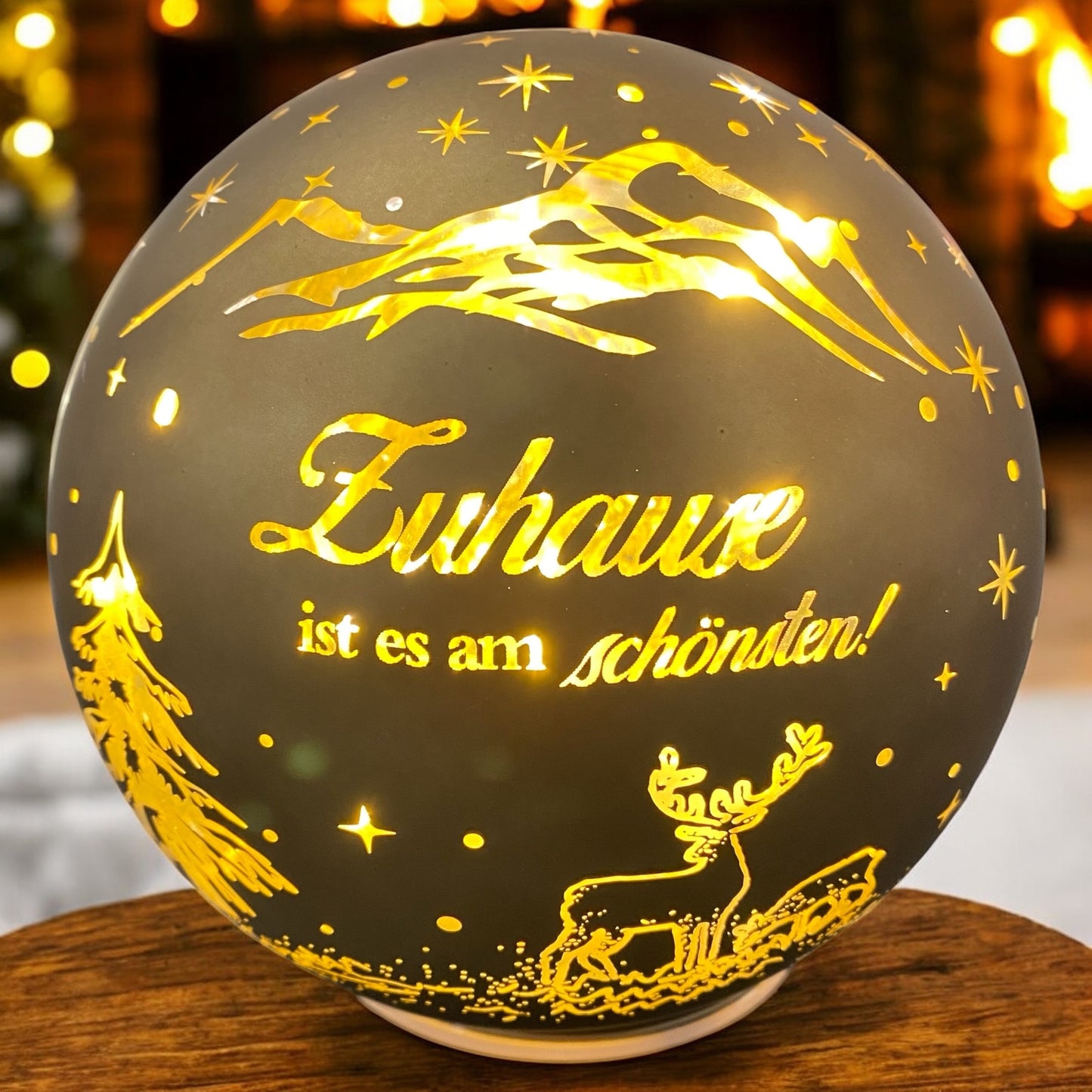 Goldene LED-Kugel mit Spruch „Zuhause ist es am schönsten“ und Rentiermotiv, strahlend in weihnachtlicher Atmosphäre.