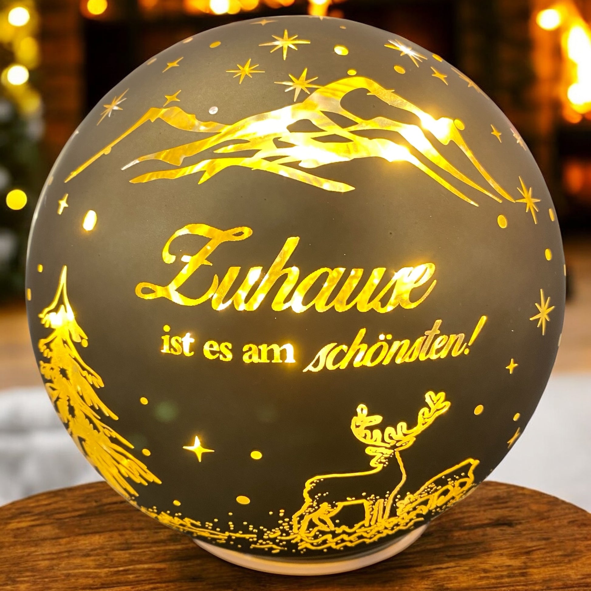 Goldene LED-Kugel mit Spruch „Zuhause ist es am schönsten“ und Rentiermotiv, strahlend in weihnachtlicher Atmosphäre.