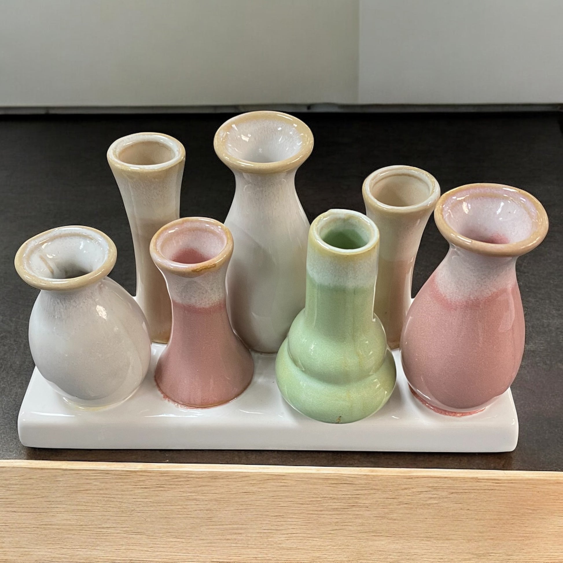Boho Deko Vasen Set aus 7 kleinen Keramik Vasen in Rosa, Grün, Beige und Grau auf creme-weißem Deko Tablett im Ambiente