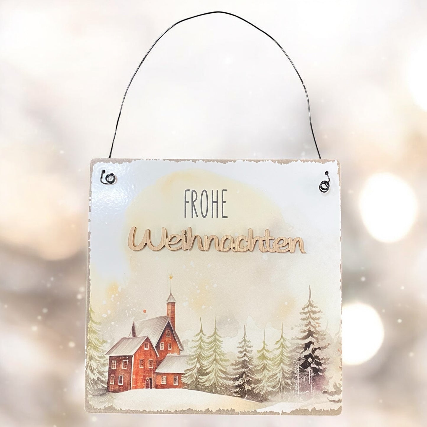 Weihnachtliches Metallschild mit der Aufschrift „Frohe Weihnachten“ und winterlicher Waldlandschaft mit roter Kirche im Schnee.

