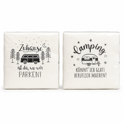 Zwei cremeweiße Papierservietten mit schwarzen Campingmotiven, Wohnmobil, Wohnwagen und Sprüchen vor weißem Hintergrund.