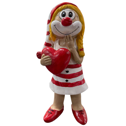 Große Clown-Dekofigur mit roter Nase in rot-weißem Outfit, ca. 20 cm groß, stehend dargestellt, ein rotes Herz vor dem Körper haltend und eine Hand am Gesicht, vor weißem Hintergrund.