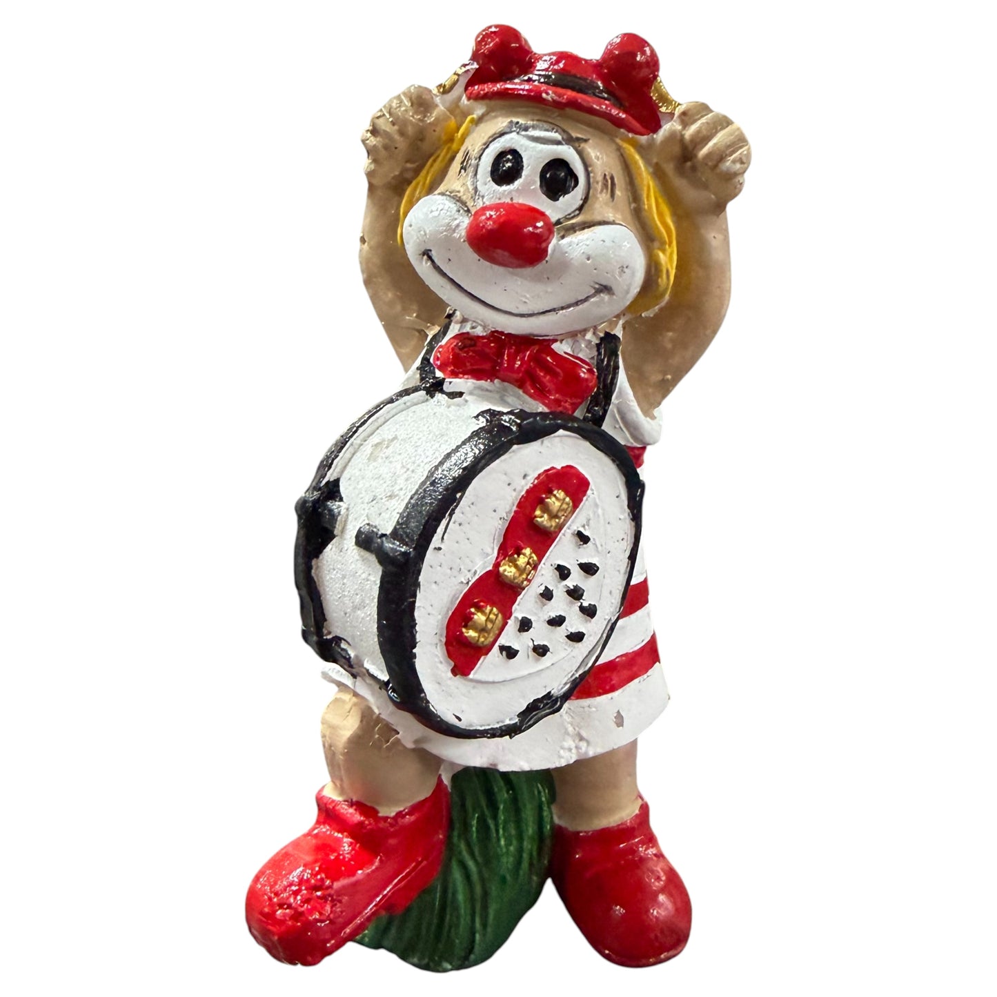 Clown-Figur mit Trommel vor dem Körper und erhobenen Armen, vor weißem Hintergrund