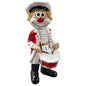 Clown-Figur mit roter Nase in rot-weißer Uniform, hält eine Trommel vor dem Körper und zwei Trommelstöcke in den Händen, vor weißem Hintergrund.