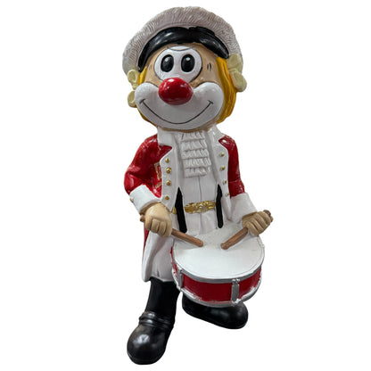 Große Clown-Dekofigur mit roter Nase in rot-weißer Trommler-Uniform, ca. 20 cm groß, stehend dargestellt und eine Trommel vor dem Körper haltend, vor weißem Hintergrund.