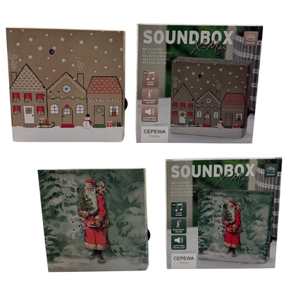 Zwei Varianten der weihnachtlichen Soundbox (Häusermotiv und Weihnachtsmann) sind zusammen mit ihren Verpackungen auf weißem Hintergrund dargestellt.