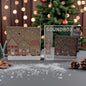 Eine weihnachtliche Soundbox mit Häusermotiv steht neben ihrer Verpackung vor einem dekorierten Weihnachtsbaum und warmem Lichterhintergrund.