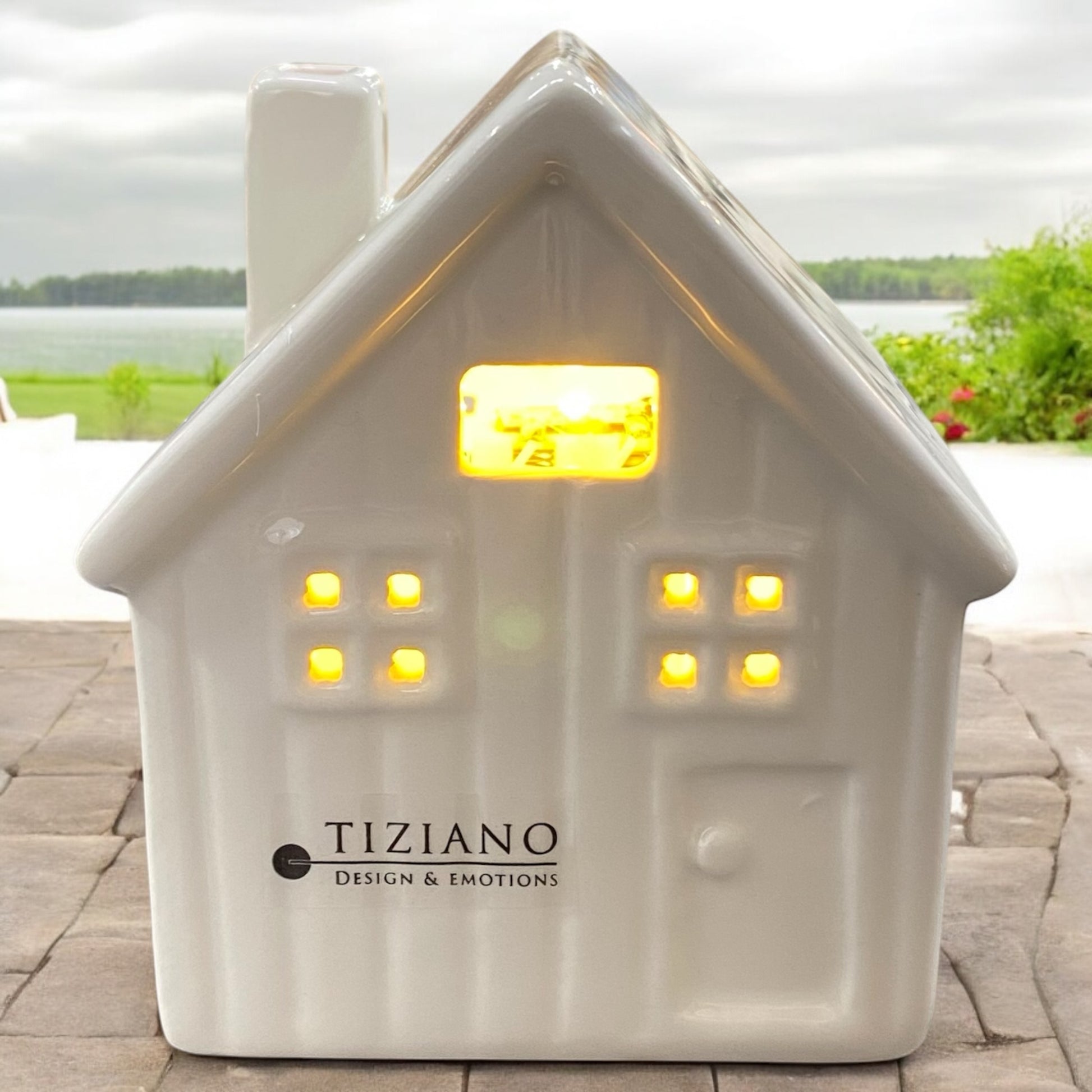 Breites Tiziano Lichterhaus aus Keramik creme-weiß mit LED-Beleuchtung und Timer-Funktion, aus dessen Fenster warmes Licht strahlt, im Ambiente