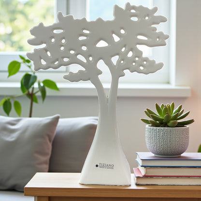 Ein einzelner dekorativer Keramikbaum in Weiß steht auf einem Tisch vor einem Fenster; das filigrane, durchbrochene Kronendesign wirkt modern und leicht.