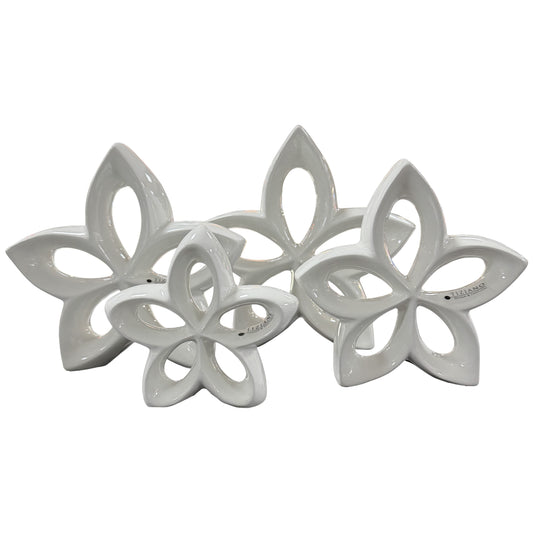 Auf weißem Hintergrund sind vier weiße, blütenförmige Keramikobjekte mit Durchbrüchen in unterschiedlichen Größen zu sehen.
