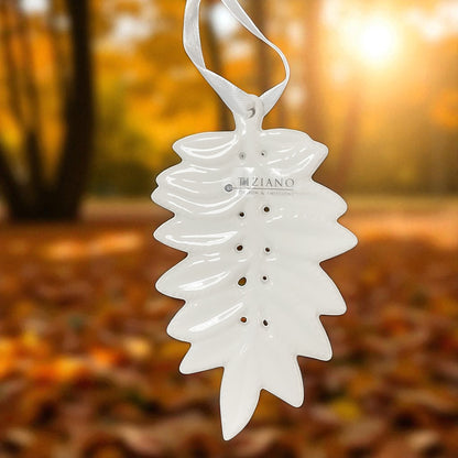 Detailansicht von weißem Keramik Hänger in Blattform mit dekorativen Lochungen und satinweißen Aufhängebändern im Ambiente