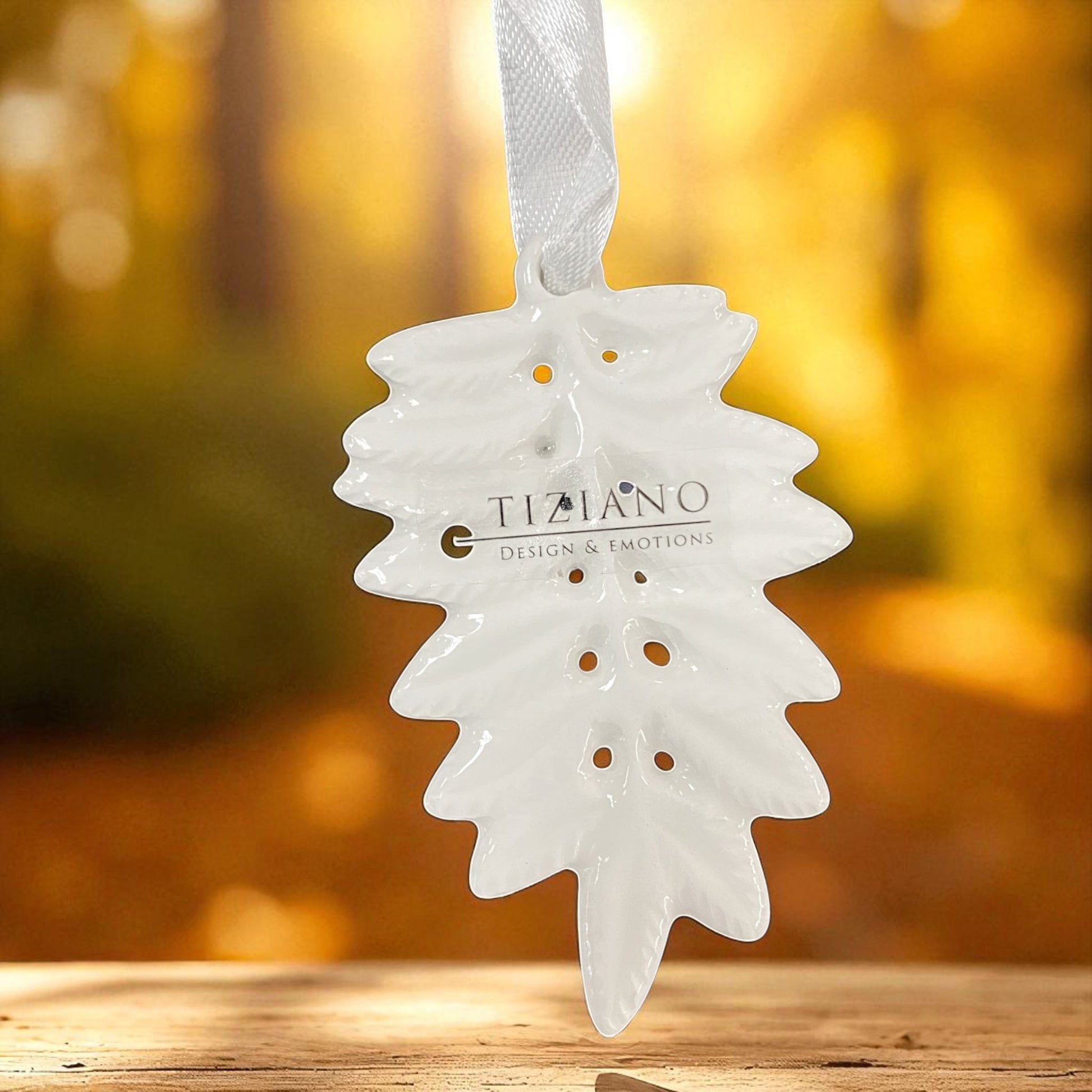 Detailansicht von weißem Keramik Hänger in Blattform mit dekorativen Lochungen und satinweißen Aufhängebändern im Ambiente