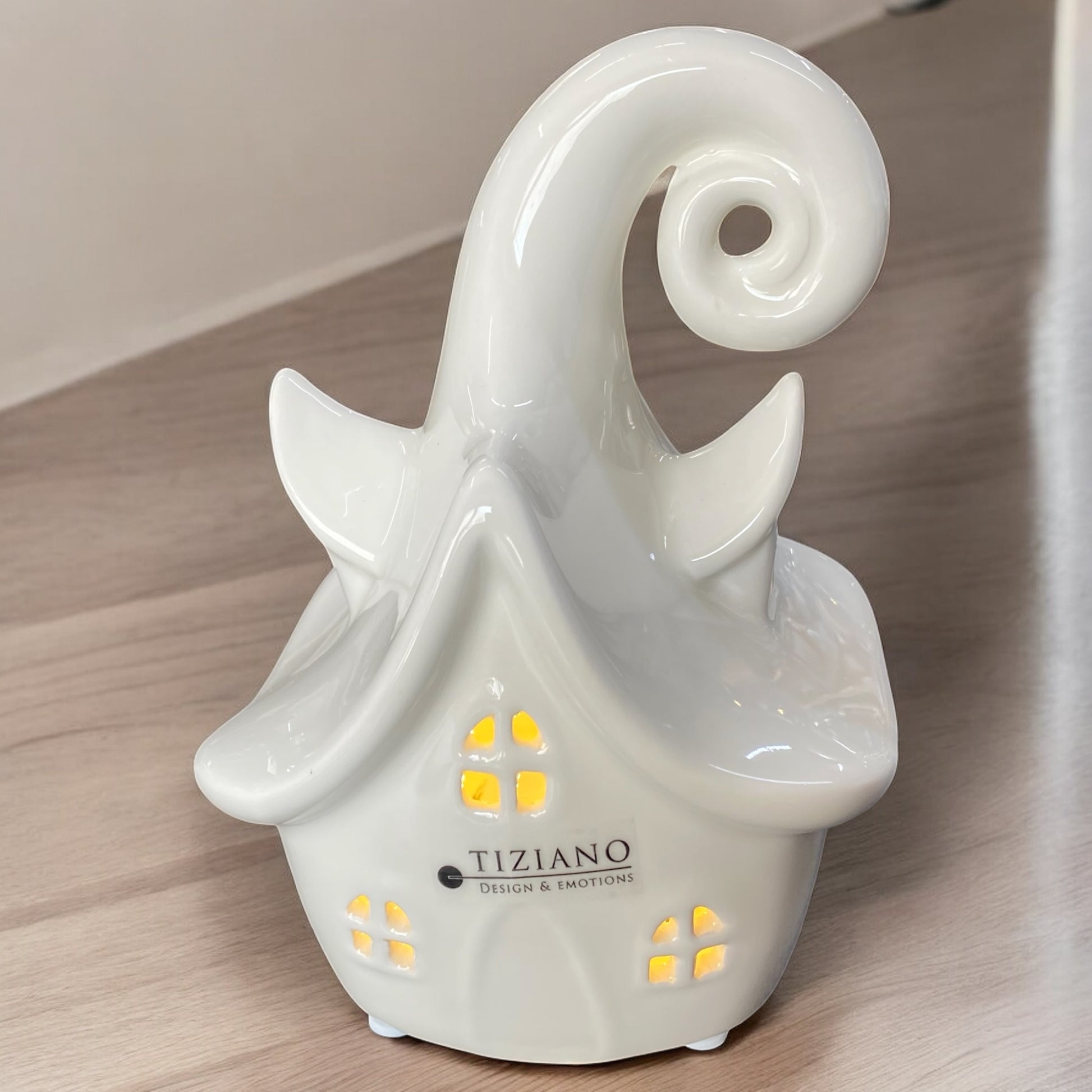 Ein weißes Keramikhaus von Tiziano mit LED Beleuchtung, Märchenhaus-Design, mit geschwungenem Dach im Ambiente