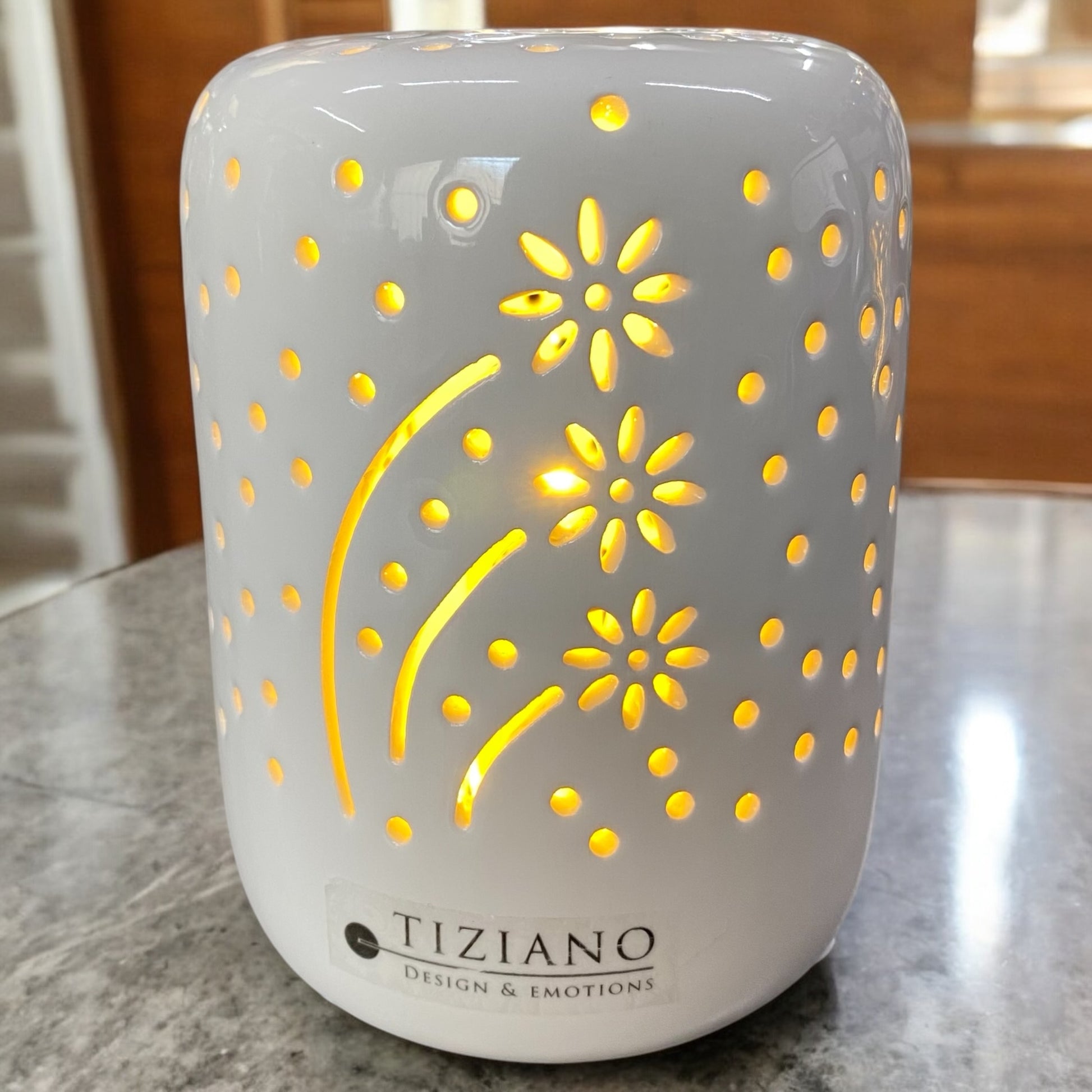 Ein creme-weißes Keramik Tiziano LED Licht mit ausgestanztem Blumenmuster und warmweißem Licht im Ambiente