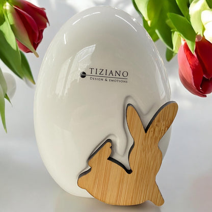 Tiziano Deko Osterei aus creme-weißer Keramik mit integriertem Deko-Hase aus Holz liegend im Ambiente