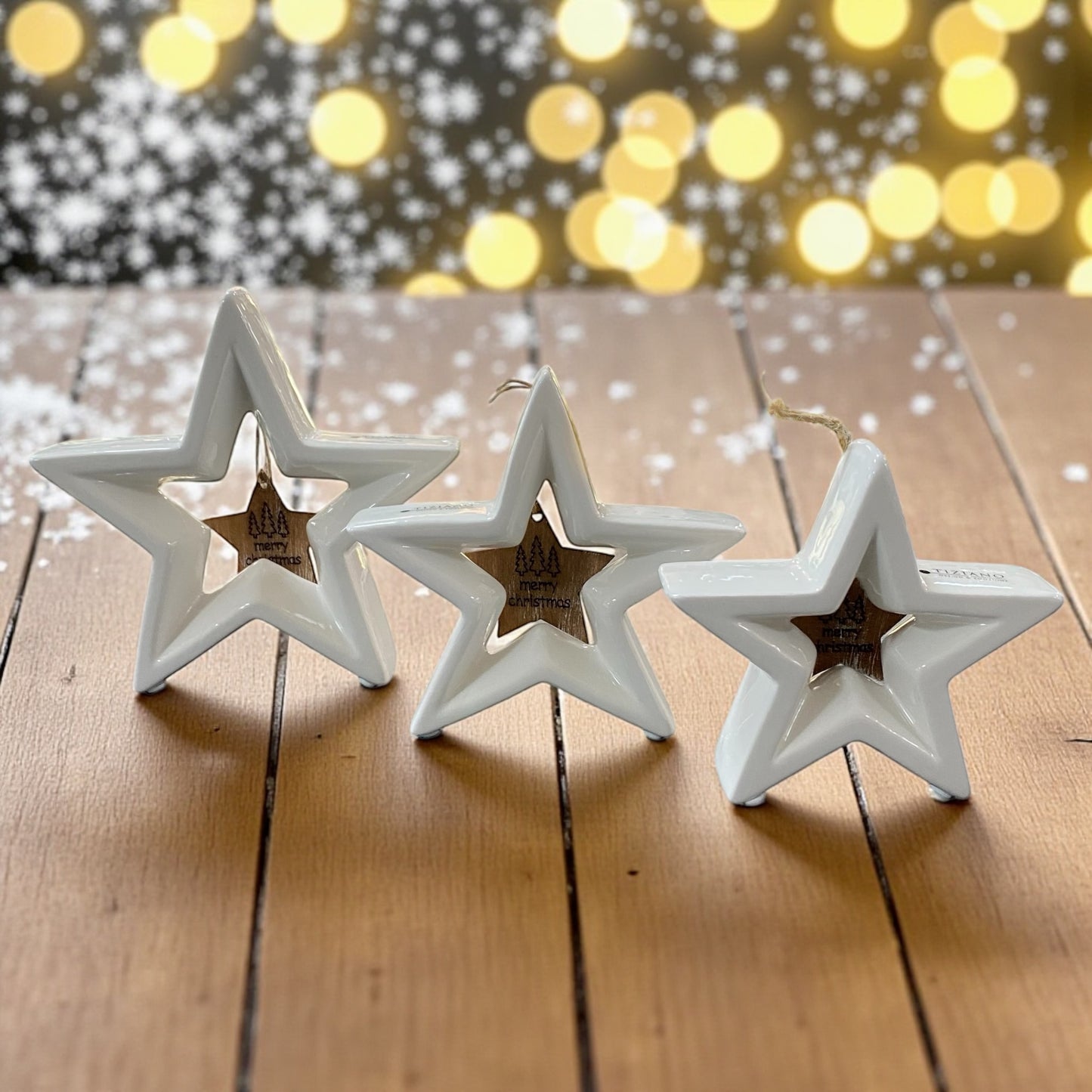 Drei stehende creme-weiße Tiziano Keramik Sterne Cascata mit hängendem Holzstern Merry Christmas im Ambiente 