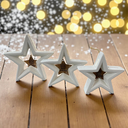 Drei stehende creme-weiße Tiziano Keramik Sterne Cascata mit hängendem Holzstern Merry Christmas im Ambiente 