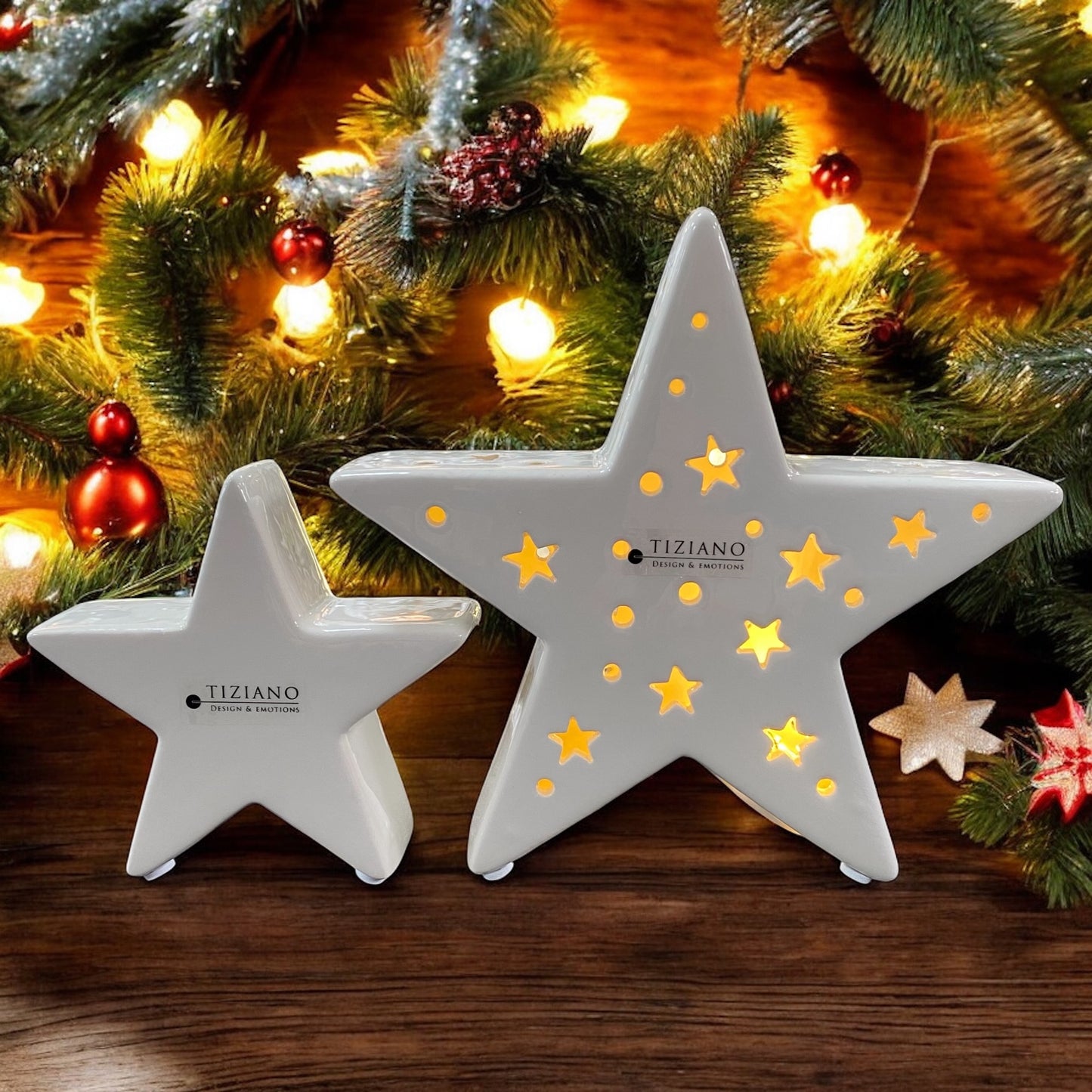 Zwei creme-weiße Keramik Sterne von Tiziano mit ausgestanzten Sternmustern und integrierter warmer LED Beleuchtung im Ambiente