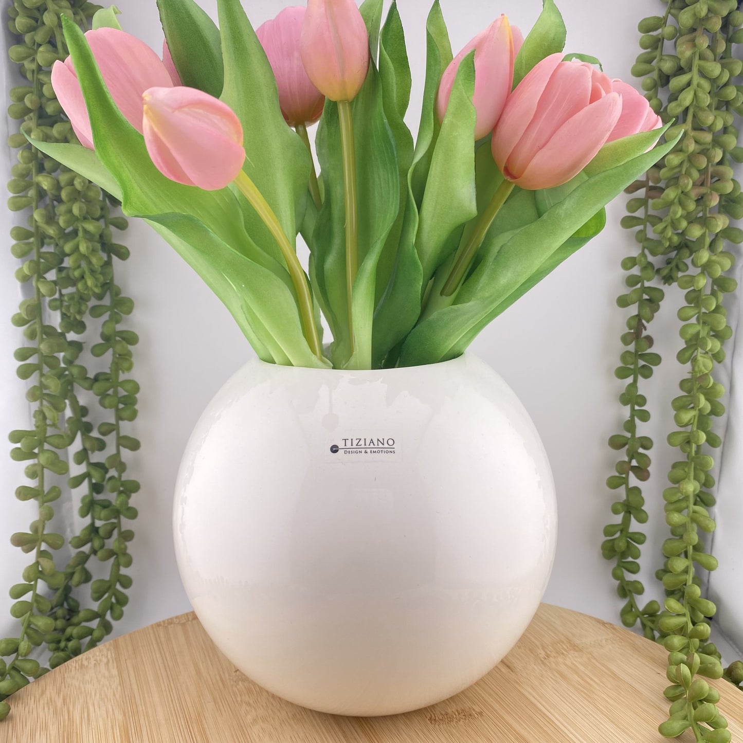 Eine große runde Blumenvase aus creme-weißer Keramik, die 17cm hoch und mit rosanen Tulpen im Ambiente platziert ist.