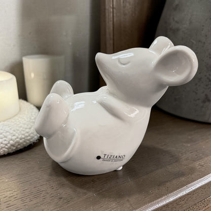 Große liegende Deko-Maus aus weißer Keramik auf einer Holzkommode neben Kerzen und Wohnaccessoires.