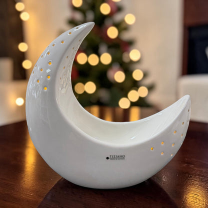 Cremeweißer Tiziano Keramik Mond mit Lochmuster und warmweißer Beleuchtung auf einem Holztisch vor einem beleuchteten Weihnachtsbaum.