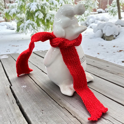 Ein creme-weißer Keramik Pinguin mit roten Schals und Mütze nach vorne von Tiziano im Ambiente